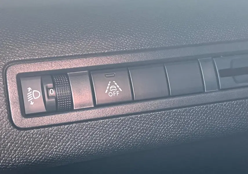 Gros plan sur les commandes de réglage des phares et d'alerte de maintien de voie du Peugeot 3008 gris Artense 2023.