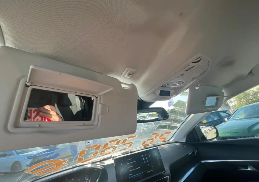 Intérieur du Peugeot 3008 2023, vue du pare-soleil côté conducteur avec miroir ouvert et tableau de bord noir visible.