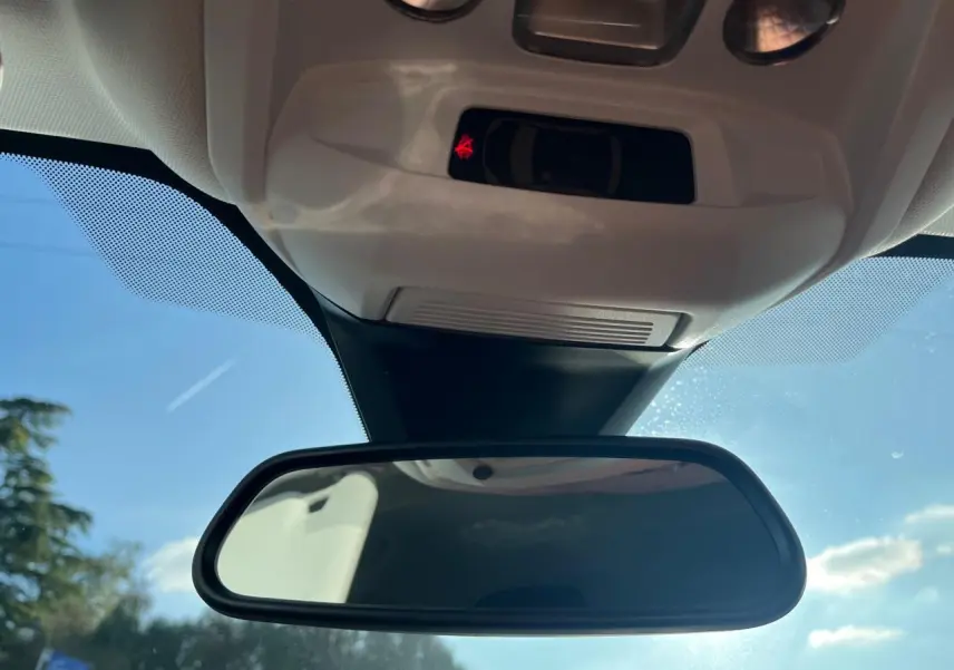 Rétroviseur intérieur de Peugeot 3008 2023, vue centrée vers le pare-brise sous un ciel bleu lumineux.