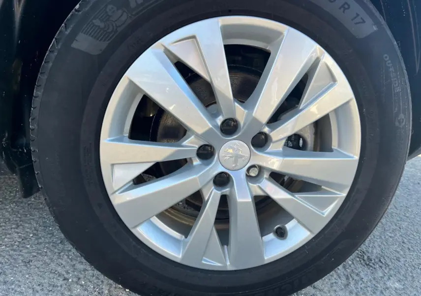Gros plan sur la jante alliage 17 pouces argentée du Peugeot 3008 gris Artense, mettant en valeur le logo lion central.