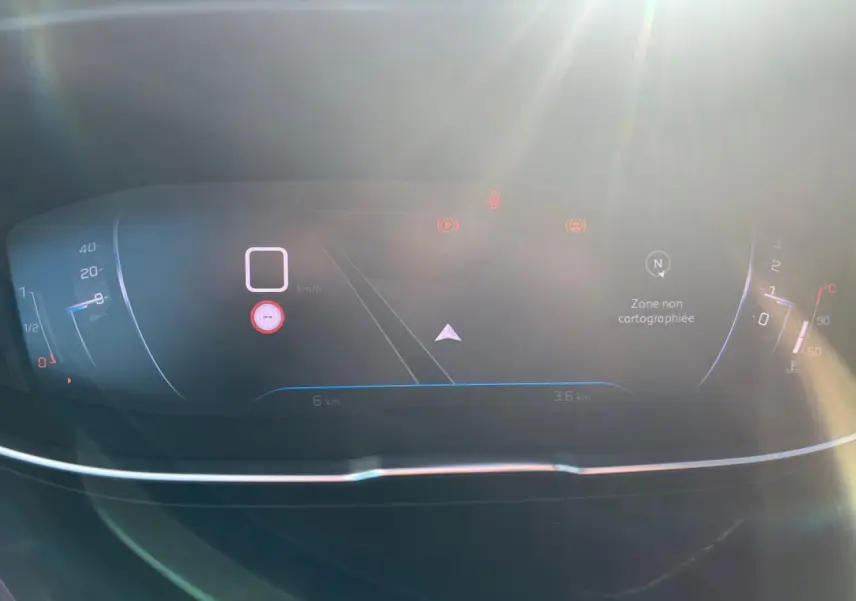 Tableau de bord numérique du Peugeot 3008 2023 affichant la navigation et la vitesse à l'arrêt, sous un éclairage solaire.