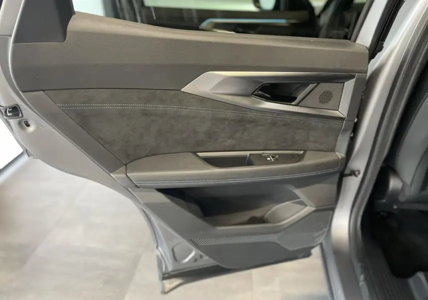 Gros plan sur la porte arrière gauche du Renault Austral gris satin mat avec insert Alcantara et surpiqûres blanches.