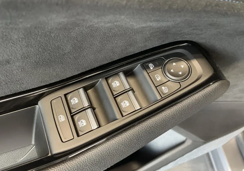 Gros plan sur les commandes des vitres électriques et rétroviseurs sur la portière côté conducteur du Renault Austral gris satin mat.