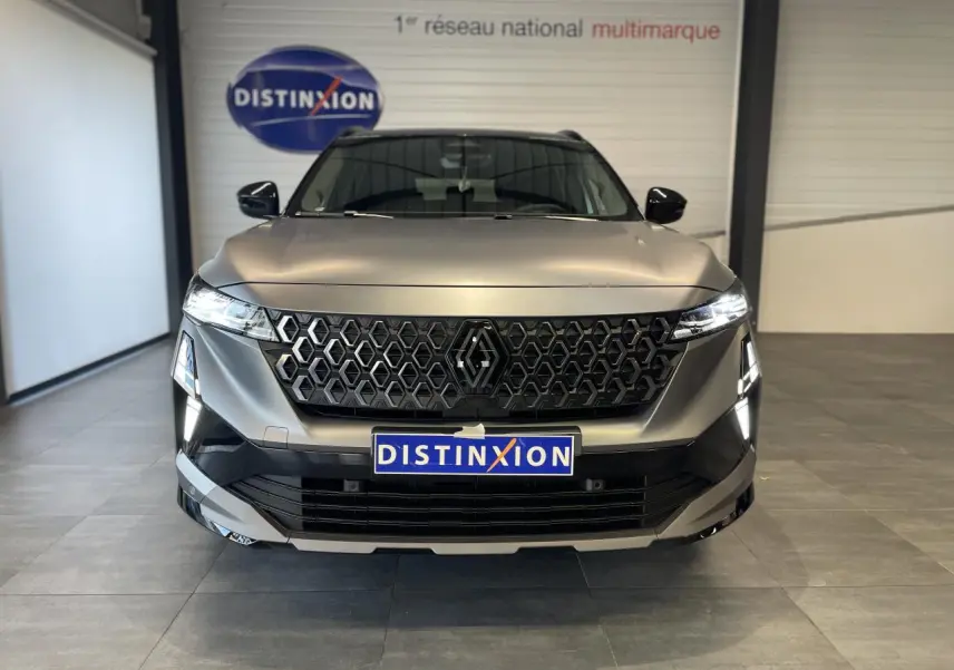 Vue frontale d'un Renault Austral gris satin mat avec calandre noire et feux LED allumés en intérieur showroom.