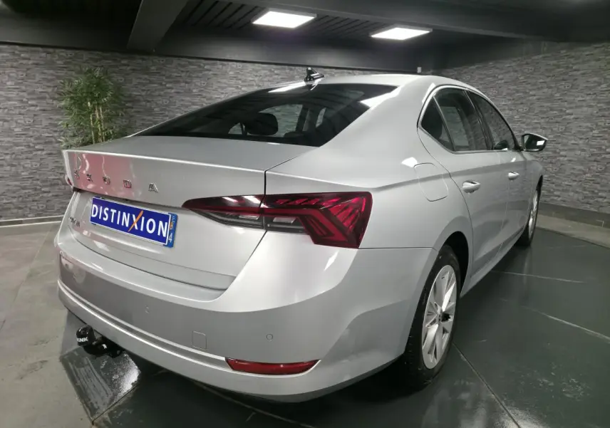Vue 3/4 arrière droite d'une Skoda Octavia gris métallisé avec attelage fixe dans un showroom.