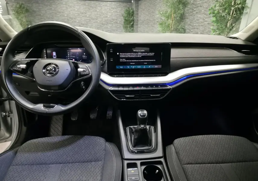 Intérieur de la Skoda Octavia 2023 vue de face, tableau de bord noir avec écran tactile et volant multifonctions.
