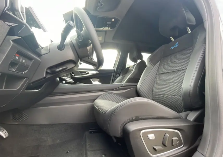 Vue intérieure côté conducteur du Renault Austral gris schiste, sièges sport semi-alcantara avec logo Alpine bleu et toit panoramique visible.