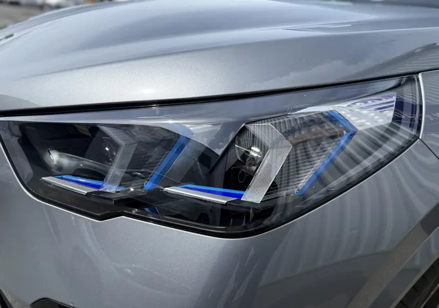 Gros plan sur le phare avant droit du BMW X2 2025 en gris Skyscraper avec détails bleus et design LED distinctif.