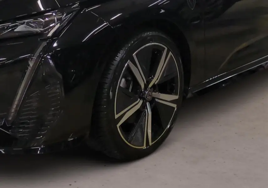 Gros plan sur la roue avant gauche et partie du pare-chocs noir Perla de la Peugeot 308 2025 avec jante alliage 18'' Kamakura.