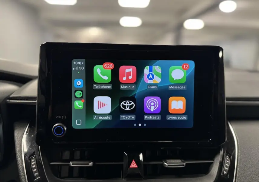 Écran tactile central de la Toyota Corolla hybride 2022 affichant Apple CarPlay dans un intérieur noir.