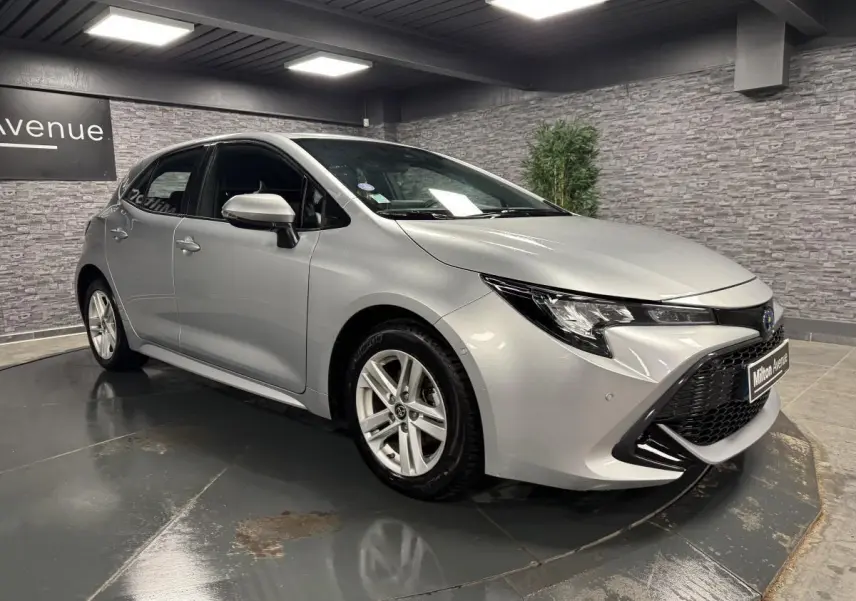 Toyota Corolla hybride gris métallisé vue 3/4 avant droit avec calandre noire et jantes alliage 16 pouces
