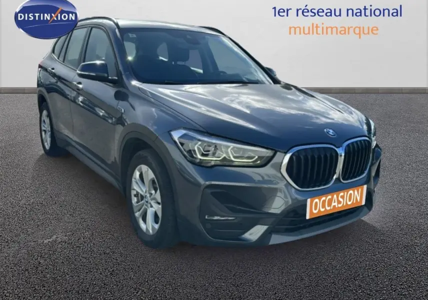 BMW X1 gris foncé vue 3/4 avant droit, avec calandre double haricot et jantes alliage 18 pouces visibles.