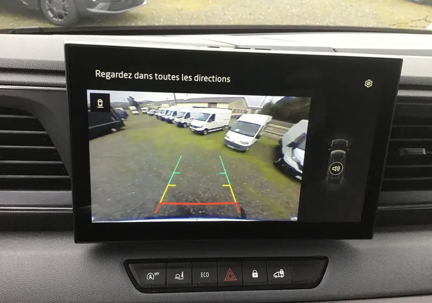 Écran central montrant la caméra de recul du Renault Master blanc, vue arrière avec plusieurs fourgons alignés.