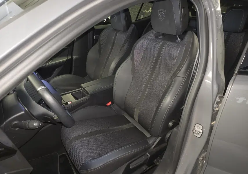 Vue intérieure côté conducteur de la Peugeot 408 gris, sièges tri-matières avec logo Peugeot brodé sur appuie-tête.
