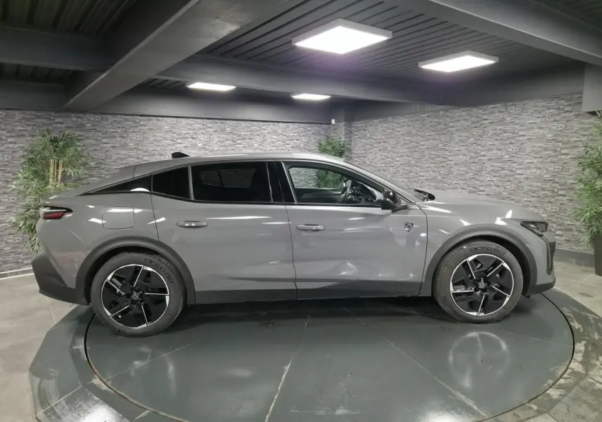 Vue latérale droite d'une Peugeot 408 gris métallisé avec jantes alliage 19 pouces et toit noir Mistral.