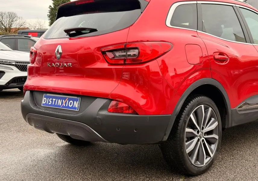 Vue 3/4 arrière droite d'un Renault Kadjar rouge flamme avec jantes alliage bi-ton et détails noirs au pare-chocs.
