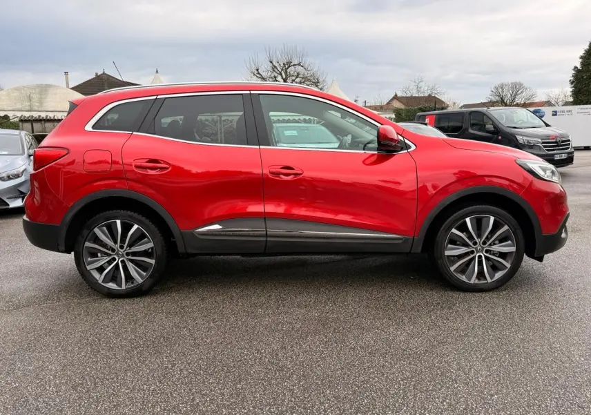 Vue de profil côté gauche d'un Renault Kadjar rouge flamme avec jantes alliage bicolores et vitres teintées.