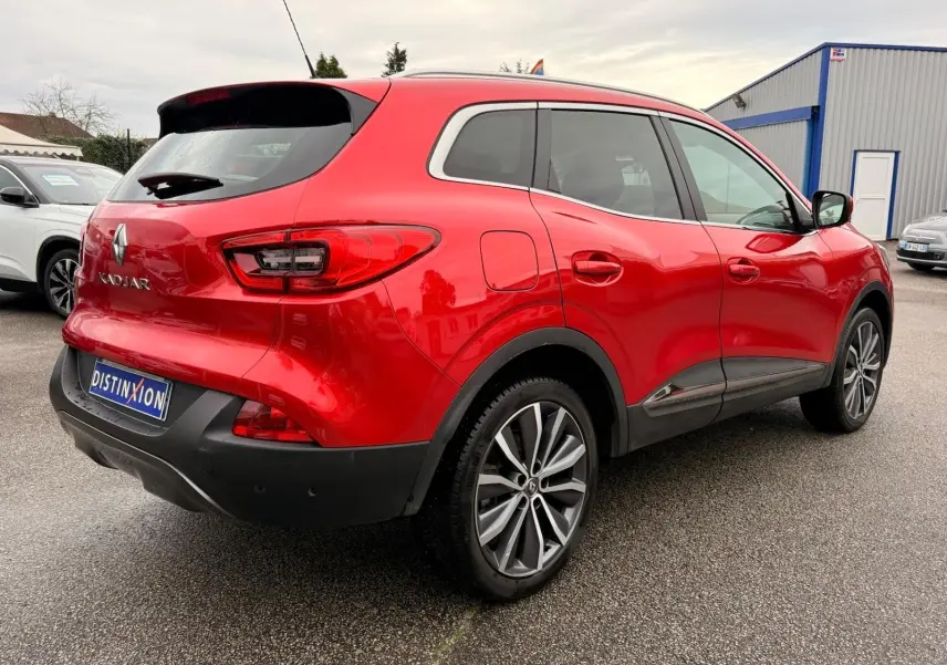 Vue 3/4 arrière droite d'un Renault Kadjar rouge flamme avec jantes alliage bi-ton et détails noirs au bas de caisse.