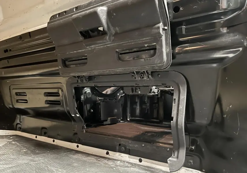 Détail de la cloison intérieure en bois noir du Nissan Primastar blanc, vue rapprochée de la zone de chargement