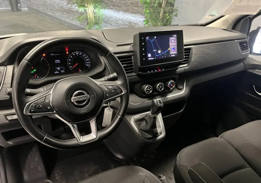 Vue intérieure côté conducteur du tableau de bord noir du Nissan Primastar avec écran tactile et volant multifonctions.