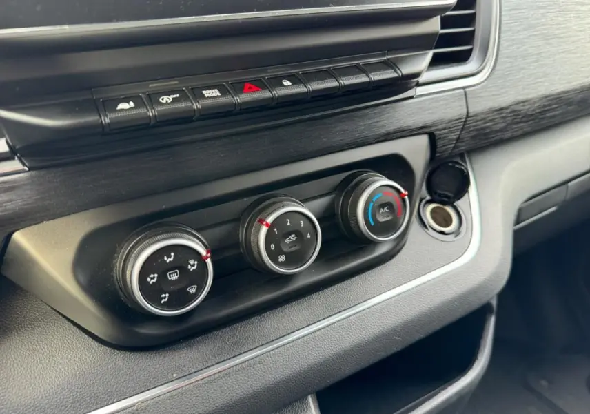 Gros plan sur les commandes de climatisation et ventilation du tableau de bord noir du Nissan Primastar blanc 2022.
