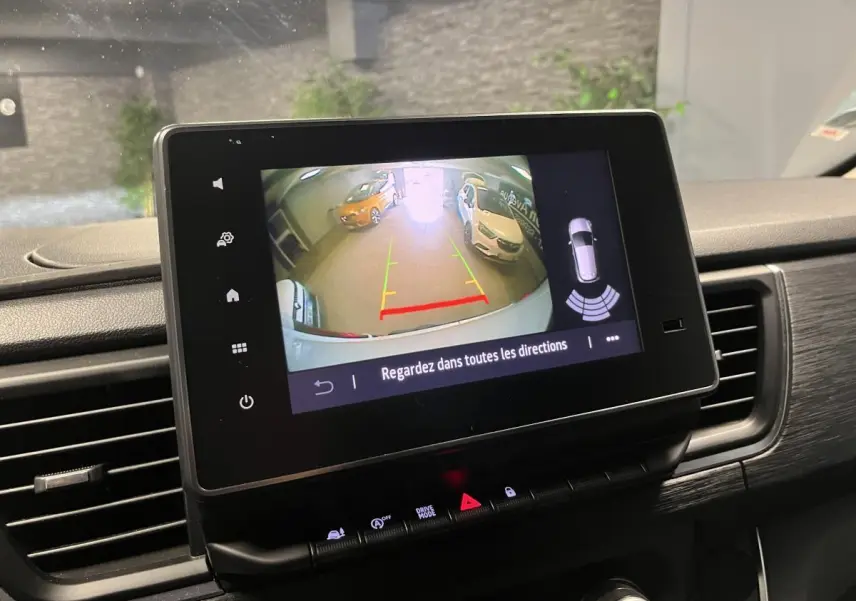 Écran tactile intérieur montrant la caméra de recul du Nissan Primastar blanc, avec vue arrière et aides au stationnement.