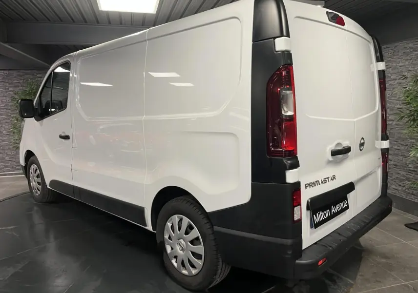 Vue 3/4 arrière droite d’un utilitaire Nissan Primastar blanc avec protections noires et jantes acier 16 pouces.