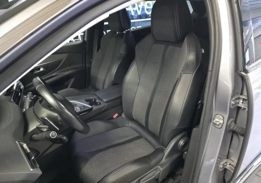 Vue intérieure côté conducteur du Peugeot 5008 gris 2022, sièges TEP et tissu Colyn avec volant cuir et console centrale.