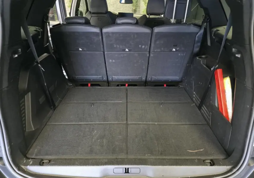 Coffre ouvert vu de l'arrière d'un Peugeot 5008 gris, montrant les sièges arrière relevés et un espace de chargement plat.