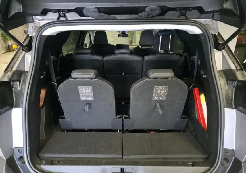Coffre ouvert d'un Peugeot 5008 gris 2022, montrant les sièges escamotés du troisième rang et l'intérieur noir.