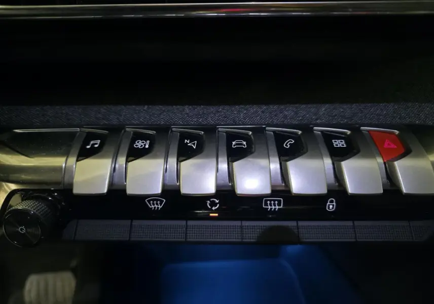 Gros plan sur les commandes argentées du tableau de bord du Peugeot 5008 2022, éclairage bleu en dessous.