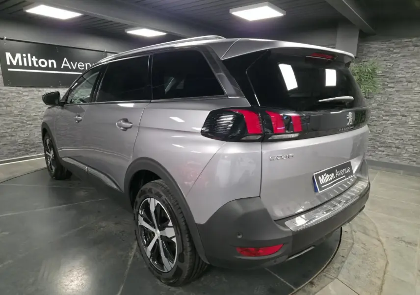 Vue 3/4 arrière droit du Peugeot 5008 gris métallisé avec jantes alliage bi-ton et vitres arrière surteintées.