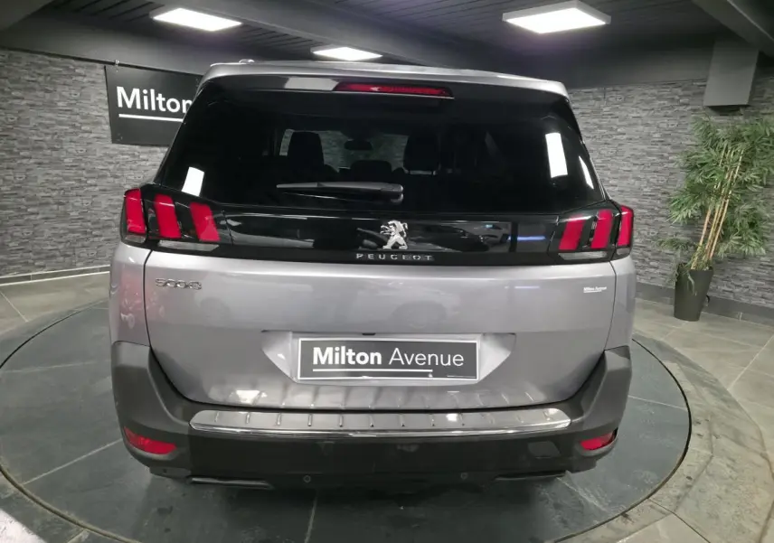 Vue arrière d'un Peugeot 5008 gris métallisé avec feux arrière à griffes rouges et lunette teintée noire.