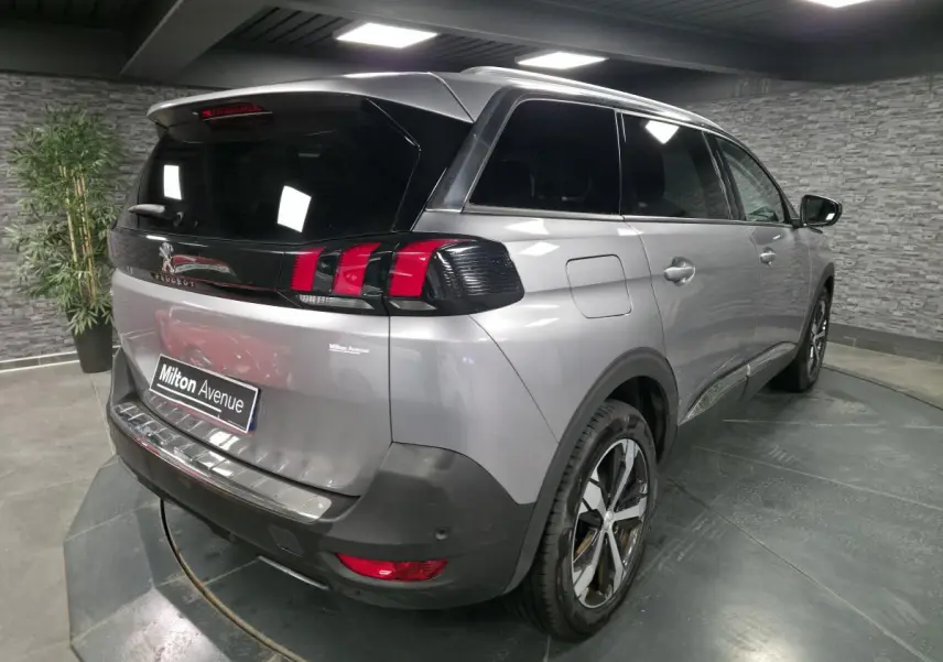 Vue 3/4 arrière droite d'un Peugeot 5008 gris métallisé avec vitres surteintées et jantes alliage bi-ton.