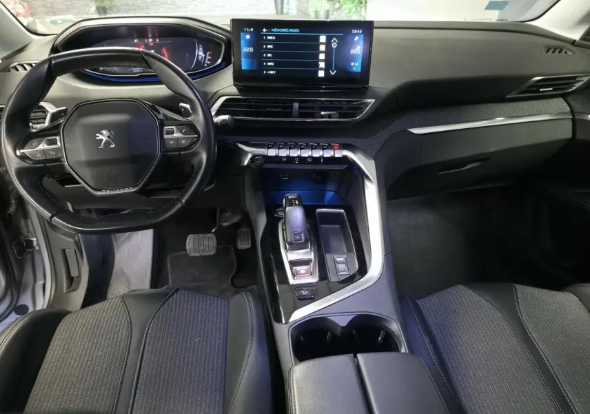 Intérieur noir du Peugeot 5008 2022, vue du poste de conduite avec volant compact et écran tactile central lumineux.