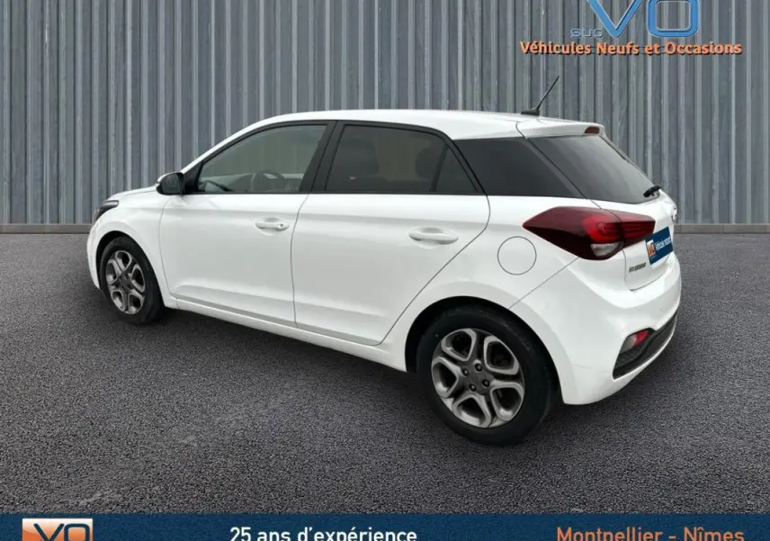 Vue côté gauche arrière d'une Hyundai i20 blanche 2019 avec vitres teintées et jantes alliage.