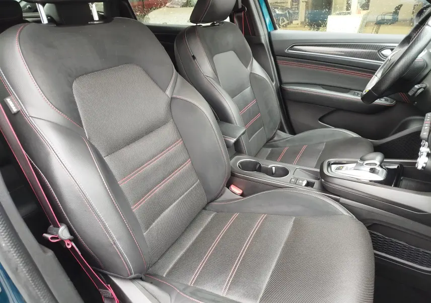 Vue intérieure côté conducteur du Renault Arkana 1.6 E-Tech bleu Zanzibar, sièges noirs avec surpiqûres rouges et console centrale.