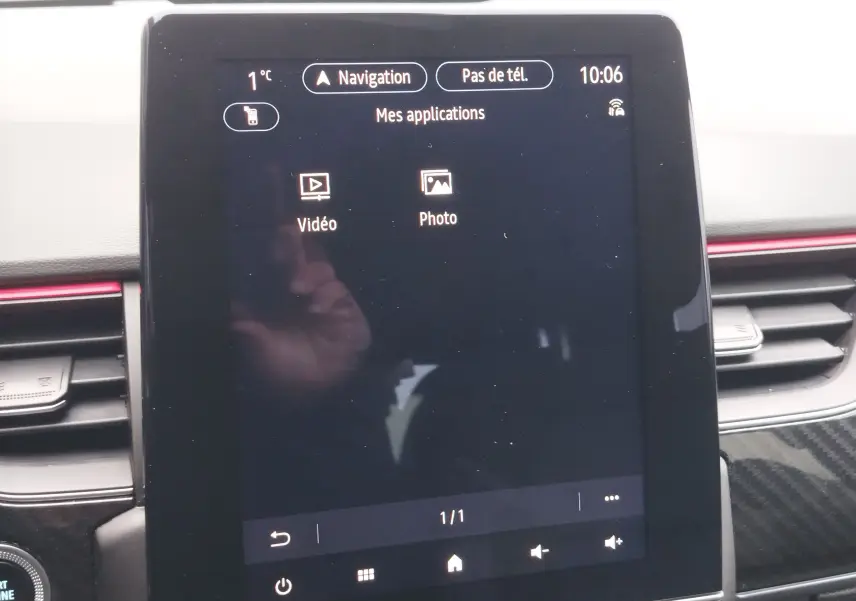 Écran tactile central de la Renault Arkana 1.6 E-Tech 2022 affichant les applications vidéo et photo, entouré de la console noire.