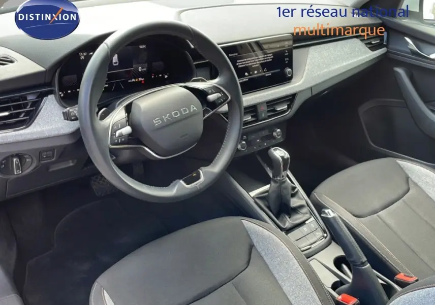 Vue intérieure côté conducteur du Skoda Scala 2025, montrant le volant, la boîte manuelle et les sièges tissu gris noir.