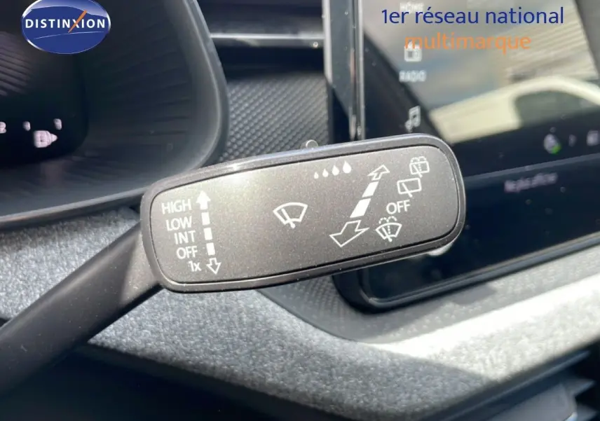 Gros plan sur la manette d’essuie-glace à gauche du volant dans l’habitacle gris noir d’une Skoda Scala blanc glacier.