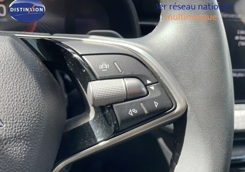 Gros plan sur les commandes multifonctions à droite du volant en cuir noir d'une Skoda Scala blanc glacier.