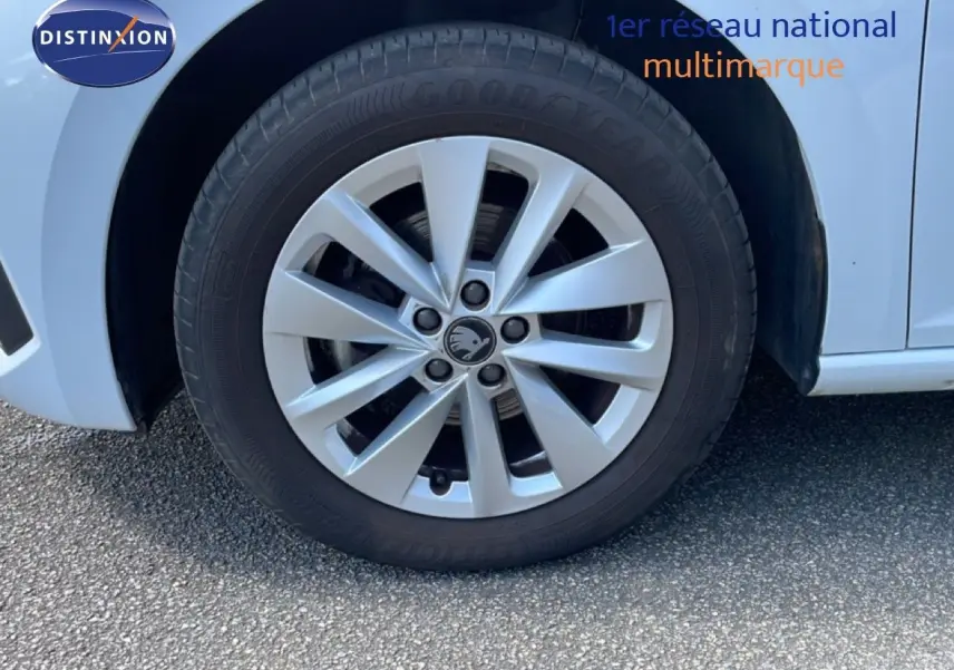 Gros plan sur la roue avant gauche d'une Skoda Scala blanc glacier avec jante alliage à 10 branches.