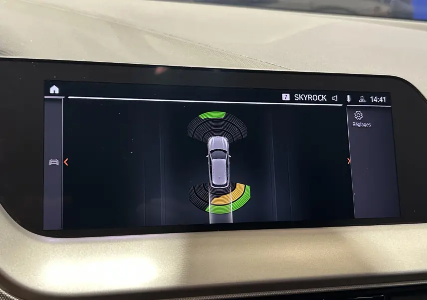 Vue rapprochée de l'écran central de la BMW Série 1 16d noir 2023 affichant l'aide au stationnement avec capteurs actifs.