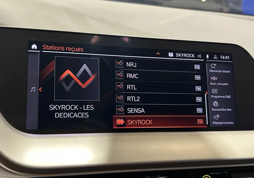Écran central de la BMW Série 1 16d 2023 affichant les stations radio, avec interface GPS et options virtuelles visibles.
