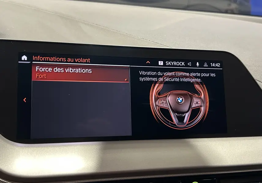 Écran central d'une BMW Série 1 16d 2023 affichant les réglages de la force des vibrations du volant en mode fort.