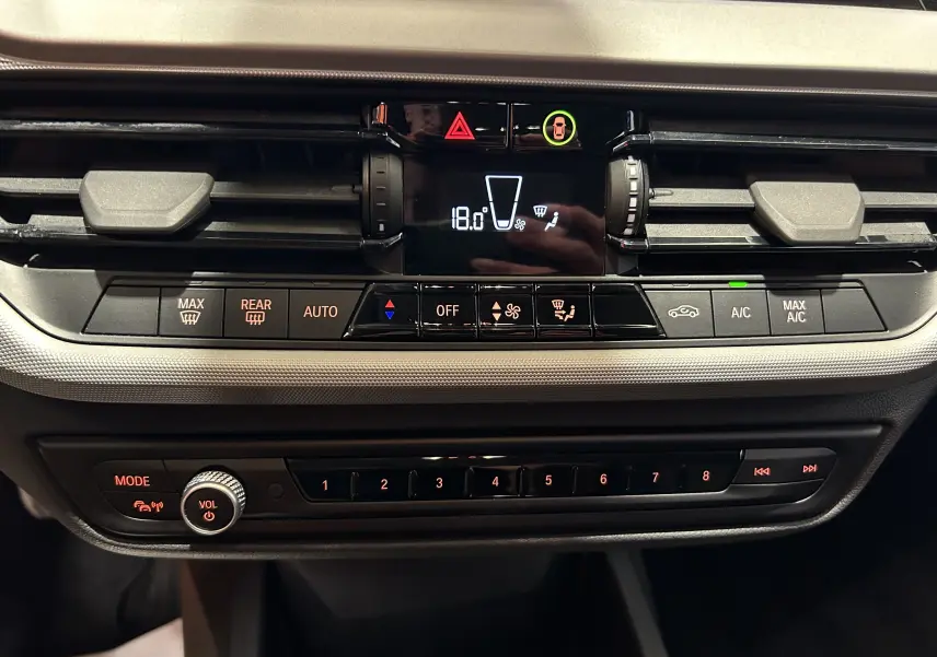 Tableau de bord de BMW Série 1 16d 2023 en noir, avec commandes climatisation digitale et réglages audio visibles.