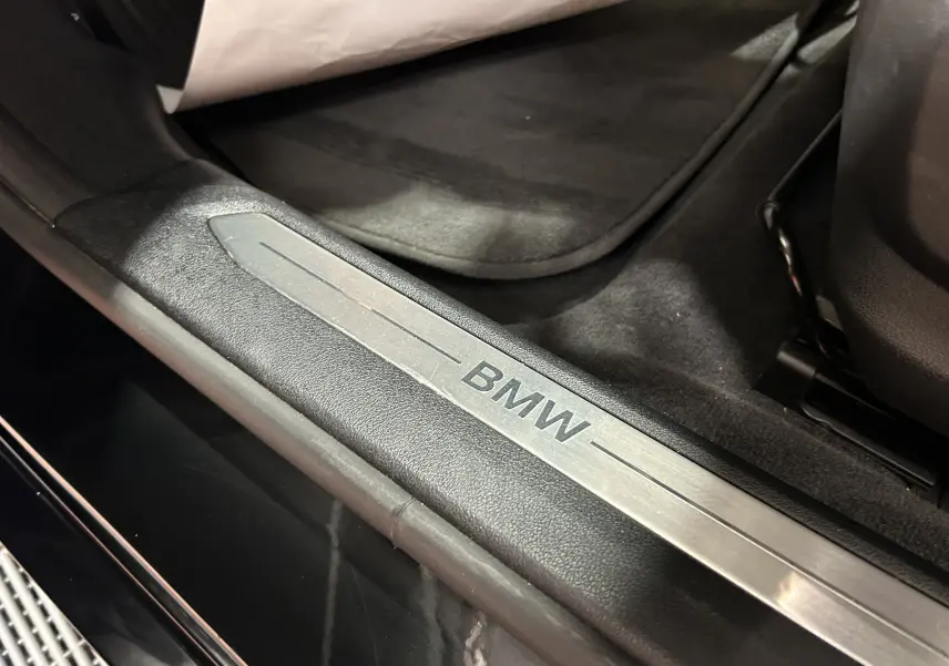 Gros plan sur la plaque de seuil de porte BMW noire à l'intérieur d'une Série 1 diesel 2023