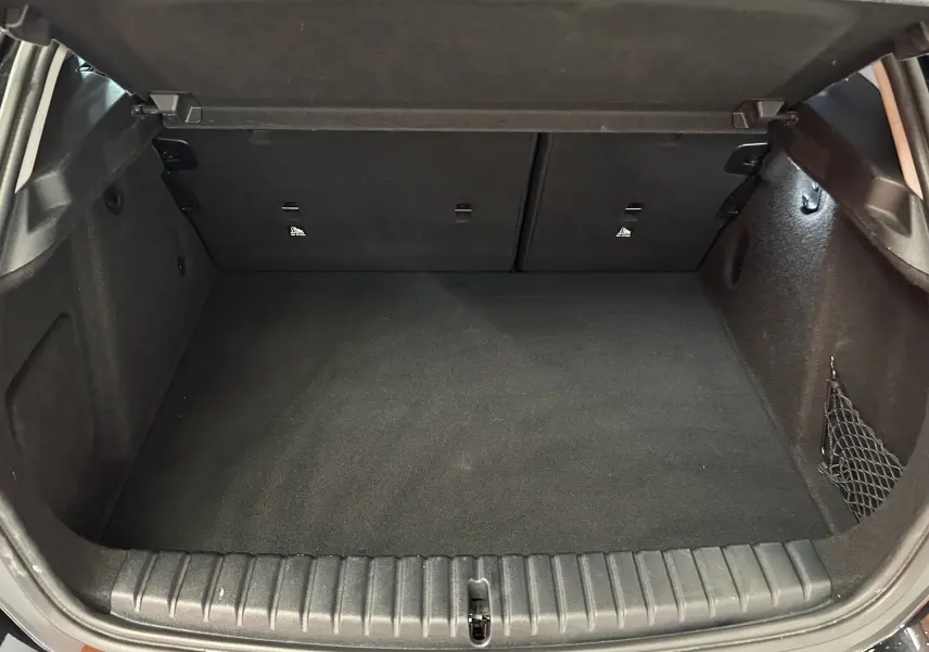 Coffre ouvert vu de l'arrière d'une BMW Série 1 noire 2023, espace de chargement propre et vide, intérieur noir.