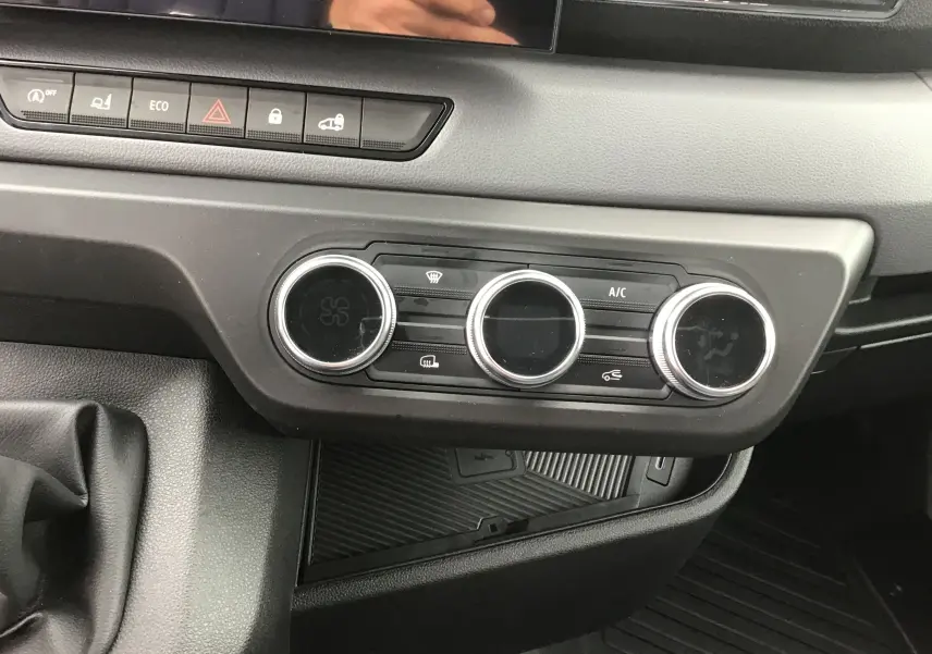 Vue rapprochée du tableau de bord gris du Renault Master 2025, montrant les commandes de climatisation et les boutons de fonction.