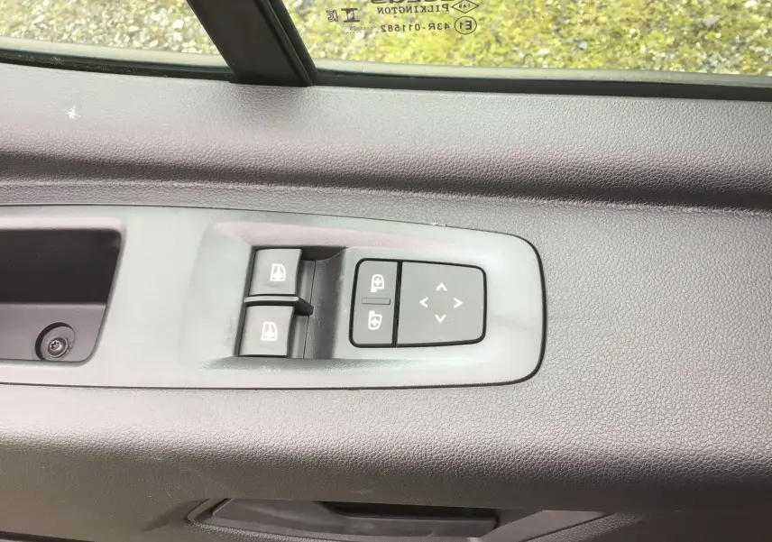 Gros plan sur les commandes des vitres et rétroviseurs électriques côté conducteur du Renault Master gris urbain.
